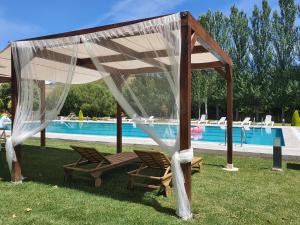 un gazebo con due sedie sotto di esso accanto a una piscina di Hotel rural Finca Vivaldi Nature & Spa a San Miguel de las Dueñas