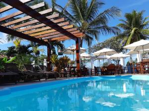 a pool with chairs and umbrellas at a resort at Lamares Pousada de Charme in Santa Cruz Cabrália