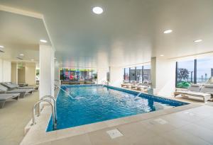 a swimming pool in a hotel lobby with chairs at Aba Luxury Studio Spa n Pool Beach resort in Mamaia Sat/Năvodari