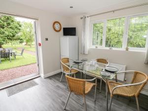 Un comedor con una mesa de cristal y sillas. en Byefield Lodge, en Great Malvern
