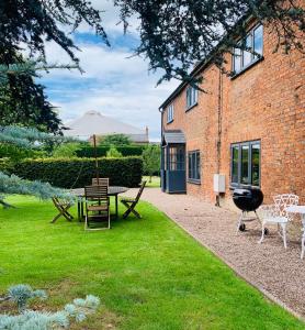 - un jardin avec une table, un parasol et un grill dans l'établissement The Cottage, Yew Tree Farm Holidays, Tattenhall, Chester, à Tattenhall