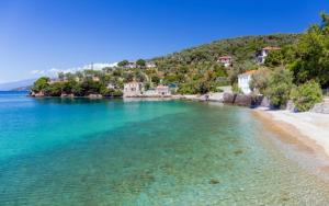 a beach with turquoise water and trees and houses at Aktaion in Milina