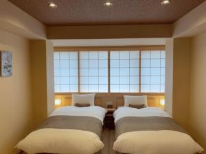 two beds in a room with a large window at Rinn Kitagomon in Kyoto