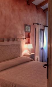 a bedroom with a bed and a lamp and a window at Villa La Quercia - Capriccioli in Abbiadori