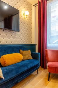 - un canapé bleu avec un oreiller jaune dans le salon dans l'établissement Hotel Europe BLV, à Paris