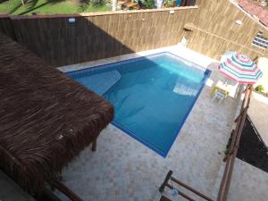 a small swimming pool with a table and an umbrella at Residencial Villa Nova SUITE in Boicucanga