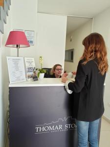 a woman standing at a counter in a hair salon at Thomar Story - Guest House in Tomar