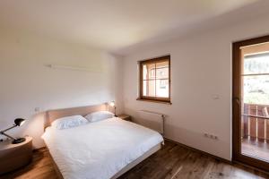 - une chambre blanche avec un lit et une fenêtre dans l'établissement Tromeja, à Rateče