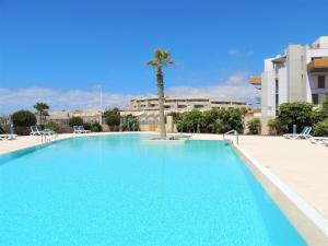 una gran piscina con palmeras y edificios en Perfect Holiday Home. en El Médano