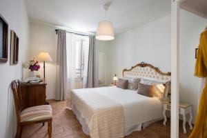 um quarto com uma cama branca e uma cadeira em Scacciapensieri Guest House em Arezzo