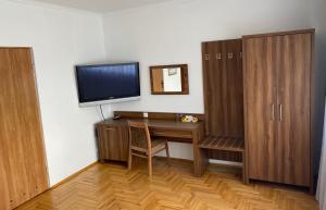 Habitación con escritorio, TV y armarios de madera. en Zajazd Maj, en Bolesław