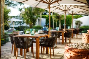 an outdoor patio with tables and chairs and umbrellas at The Atlantic Hotel in St Brelade