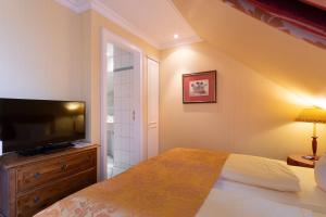 a bedroom with a large bed and a television at Strandhotel Sylt Westerland in Westerland