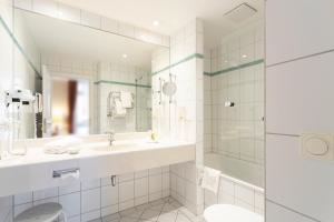 a white bathroom with a sink and a shower at Strandhotel Sylt Westerland in Westerland