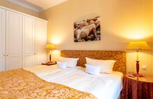 a bedroom with a large bed with white sheets and two lamps at Strandhotel Sylt Westerland in Westerland