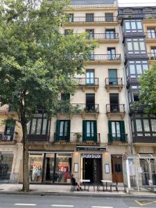 a building on a street with a tree in front of it at Pensión Urkia in Donostia-San Sebastián