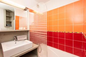 a bathroom with a sink and orange and red tiles at Résidence Le Chamois d'Or in Val Thorens