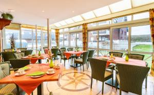 a restaurant with tables and chairs and windows at Strandhotel Sylt Westerland in Westerland
