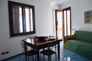 ein Wohnzimmer mit einem Tisch und einem grünen Sofa in der Unterkunft Case Vacanza Vivaldi in Marinella di Selinunte