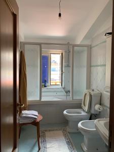 a bathroom with a toilet and a sink and a window at CASA SUL MARE in Castel di Tusa