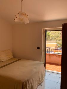 a bedroom with a bed and a view of a balcony at CASA SUL MARE in Castel di Tusa