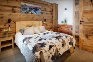 een slaapkamer met een bed en een houten muur bij Chalet Sabaroc - OVO Network in La Giettaz