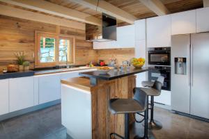a kitchen with white cabinets and a counter with a stool at Chalet Sabaroc - OVO Network in La Giettaz