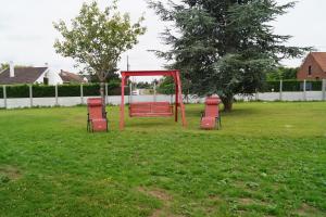 a red swing set in a field of grass at À La Maison Du Bonheur in Audruicq