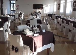 un comedor con mesas y sillas blancas, una mesa y un sillón en Hotel Villa Damanti, en Licata