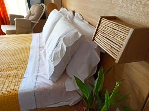 sypialnia z łóżkiem z białymi poduszkami i rośliną w obiekcie Cozy Residences in the center of Volissos Village - Lydia Lithos- w mieście Volissos