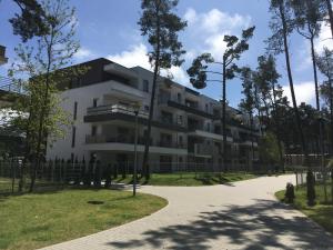 a large white building with trees in front of it at Apartament Baltic Park - BEL MARE 2 in Pogorzelica