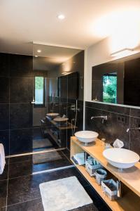 un bagno con tre lavandini e un grande specchio di B&B Hier en Nu a Heusden