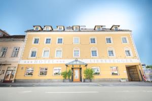 duży żółty budynek siedzący po stronie ulicy w obiekcie Hotel Liebetegger-Klagenfurt w mieście Klagenfurt