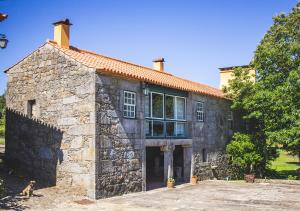 a stone building with a dog sitting in front of it at Casa da Quinta do Outeiro in Viana do Castelo