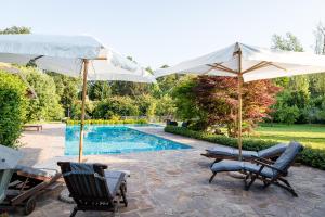 two chairs and umbrellas next to a swimming pool at Relais Dei Cesari in Borgo Ticino