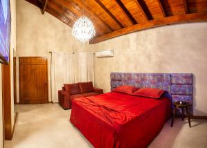 1 dormitorio con 1 cama roja y 1 silla en BANGALÔS REFÚGIO DO VALE, en Santa Maria do Erval