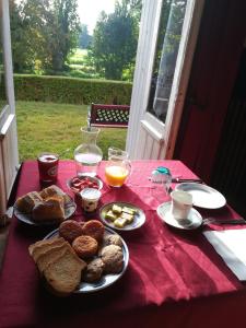 einen Tisch mit Teller mit Lebensmitteln auf einem roten Tischtuch in der Unterkunft Domaine de Champ rose in Saint-Laurent-de-Belzagot