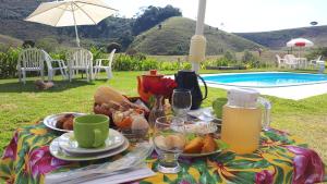 a picnic table with food and drinks and a pool at Pousada Chalés dos Montes in Santana dos Montes