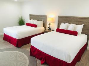 a hotel room with two beds with red pillows at The Landing at Morro Bay in Morro Bay