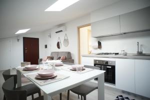 - une cuisine blanche avec une table et des chaises blanches dans l'établissement Appartamento Sweet Rose, à Ispica
