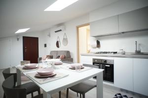 a white kitchen with a white table and chairs at Appartamento Sweet Rose in Ispica