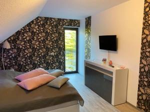 1 dormitorio con 1 cama y TV en la pared en Haus Katarina en Wiesmoor