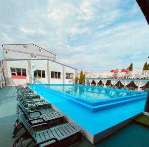 a large swimming pool with chaise lounge chairs on top of a building at Black Lord Hotel in Târgu-Mureş