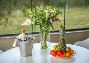 a table with a vase of flowers and a plate of fruit at BANGALÔS REFÚGIO DO VALE in Santa Maria do Erval