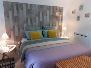 Escale en baie. في Pontaubault: غرفة نوم بسرير كبير مع مخدات صفراء وزرقاء