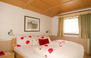 フィンケンベルクにあるHaus Niedereggerのベッドルーム1室(赤い花の白いベッド1台付)