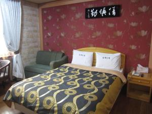 een hotelkamer met een bed en een stoel bij Jeju Olleh Hotel in Jeju-stad