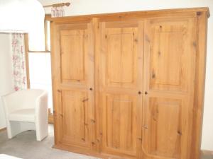 un armario de madera en una habitación con una silla blanca en Ferienwohnung Peschl Langdorf Bayerischer Wald, en Langdorf