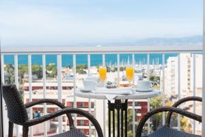 Una mesa con dos vasos de jugo de naranja en un balcón. en Hotel Torre Azul & Spa - Adults Only, en El Arenal