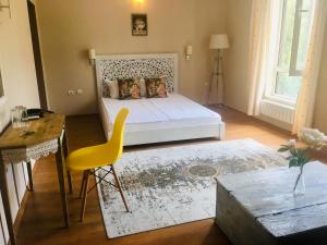 a bedroom with a bed and a table and a yellow chair at Hotel Shterev Karlovo in Karlovo